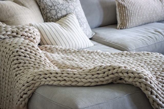A couch with a blanket on top of it A couch with a blanket on top of it